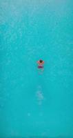 vertical vídeo. aéreo Visão Como uma homem mergulhos para dentro a piscina e nada. video