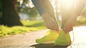 mujer atadura cordones de los zapatos mientras trotar o caminando a puesta de sol. video