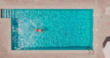 Aerial view as a man swims in the pool. Slow motion video