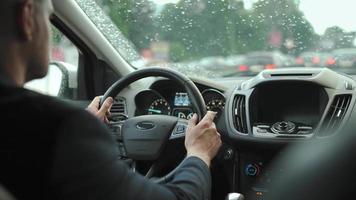 Mens schijven een auto langs de weg in de stad gedurende de regen. video