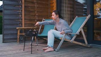 Woman makes a barbecue on the terrace outdoors. Home rest in warm evening video