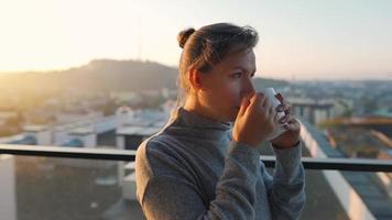 mujer empieza su día con un taza de té o café en el balcón a amanecer video