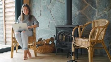 Woman using laptop while sitting near the fireplace. video