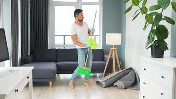 Man cleaning the house and having fun dancing with a broom. video