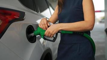 Woman inserts a fuel gun in a gas tank to refuel a car video