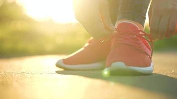 vrouw koppelverkoop schoenveters terwijl jogging of wandelen Bij zonsondergang. video