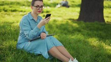donna utilizzando smartphone mentre seduta nel parco dopo finitura all'aperto opera video