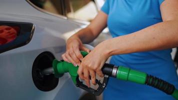 femme inserts une carburant pistolet dans une gaz réservoir à ravitailler une voiture video