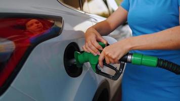 Woman inserts a fuel gun in a gas tank to refuel a car video