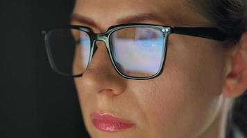 kvinna i glasögon ser på de övervaka och surfing internet på natt video