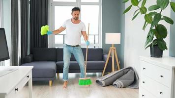 hombre limpieza el casa y teniendo divertido bailando con un escoba. lento movimiento video