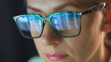 mulher dentro óculos olhando em a monitor e trabalhando com gráficos às noite video