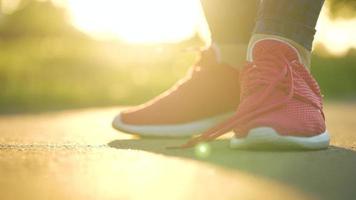 mujer atadura cordones de los zapatos mientras trotar o caminando a puesta de sol. lento movimiento video