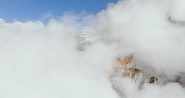 Aerial view of the clouds, rocky mountains are visible through the. video