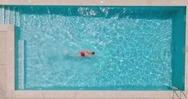 Aerial view of a man in red shorts swimming in the pool. video