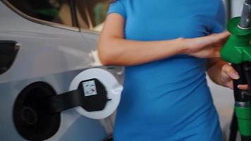femme inserts une carburant pistolet dans une gaz réservoir à ravitailler une voiture video