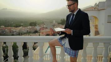 Man in a jacket and underwear negotiates at home on the terrace of a villa video