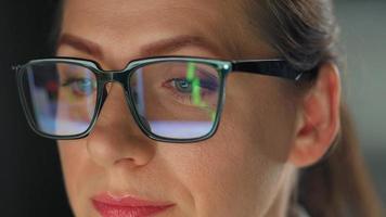 Woman in glasses looking on the monitor and working with charts at night video