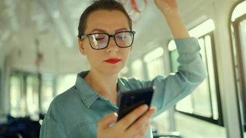 Public transport. Woman in glasses in tram using smartphone. Slow motion