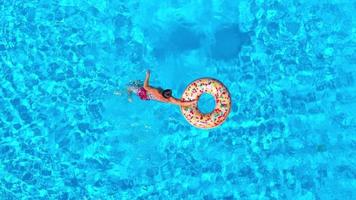 Aerial view of a man in red shorts swimming in the pool with an inflatable donut