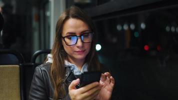 offentlig transport på natt. kvinna i glasögon i spårvagn använder sig av smartphone video