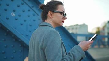 Woman in a coat walking around the city in the early morning with smartphone video