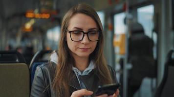 Public transport. Woman in glasses in tram using smartphone, slow motion video