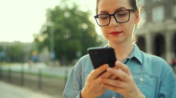 Frau mit Smartphone während Stehen draußen beim Sonnenuntergang video