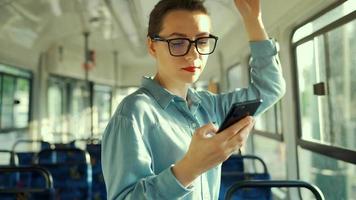 Public transport. Woman in glasses in tram using smartphone. Slow motion video