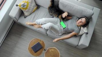 Relaxed woman in headphones with smartphone with green mock-up screen video