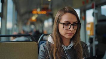 Public transport. Woman in glasses in tram using smartphone, slow motion