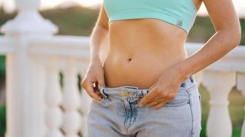 mujer disfrutar peso pérdida a hogar. hembra en antiguo pantalones después exitoso dieta.