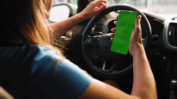 vrouw bestuurder gebruik makend van een smartphone binnen de auto. Chroma sleutel smartphone met groen video