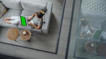 Overhead shot of woman using laptop with green mock-up screen video