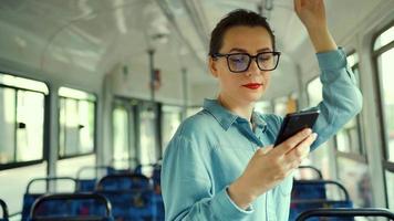 Public transport. Woman in glasses in tram using smartphone
