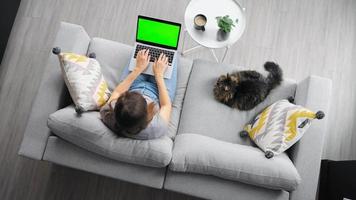 Overhead shot of woman using laptop with green mock-up screen video