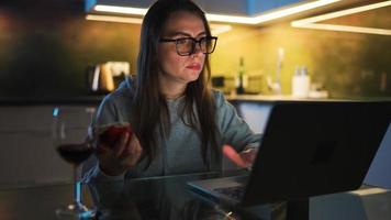 donna è seduta nel il cucina e Lavorando su un' il computer portatile e mangiare il Mela video