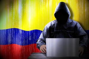 Anonymous Hooded Hacker and Flag Of Colombia, Binary Code - Cyber Attack Concept photo