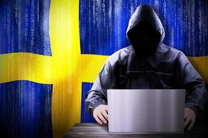 Anonymous Hooded Hacker and Flag Of Sweden, Binary Code - Cyber Attack Concept photo