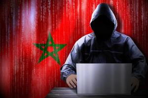 Anonymous Hooded Hacker and Flag Of Morocco, Binary Code - Cyber Attack Concept photo