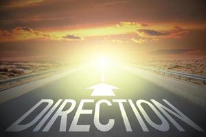 Direction word and arrow on a road and sunset sky - confusion concept photo