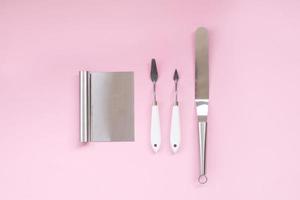 Metal pastry chef's tools on a pink background. Spatulas and spatulas for making cake photo