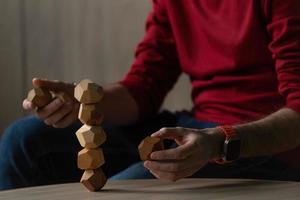 Male hands put together different figures from wooden polyhedrons, eco games for adults and children, antistress toys made of natural wood