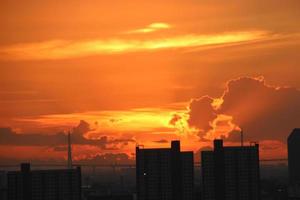brillante dorado nublado cielo en puesta de sol antecedentes en ciudad edificio pueblo foto