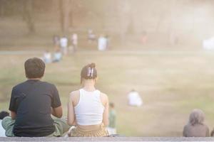 joven Pareja sentado acecho puesta de sol en noche y chateando felizmente. joven Pareja se sienta y negociaciones a discutir y Rápido su corazones a cada otro. concepto de amor y amistad para cada otro. foto