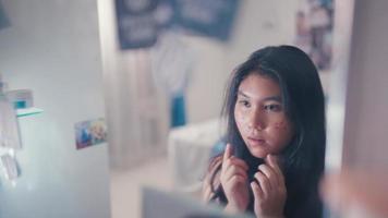 an Asian teenager looks stressed when he looks at his face in the mirror after being bullied video