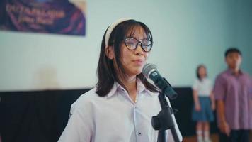 a high school student recites a poem in front of the judges while participating in a competition video