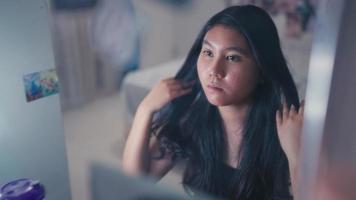 an asian teenager looks in the mirror with a feeling of insecurity because her face video