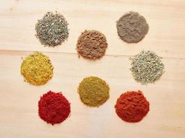 Spices circles 8 pieces on a wooden background. Garlic, coriander, for meat, for salad, red pepper, black pepper photo