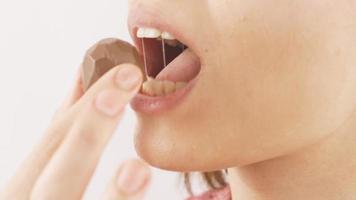 mulher comendo chocolate com coração dentro fechar-se. comendo chocolate. fechar-se mulher come coração em forma chocolate. video